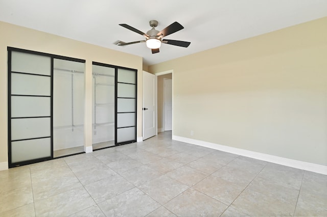 unfurnished bedroom with ceiling fan, two closets, and light tile patterned floors