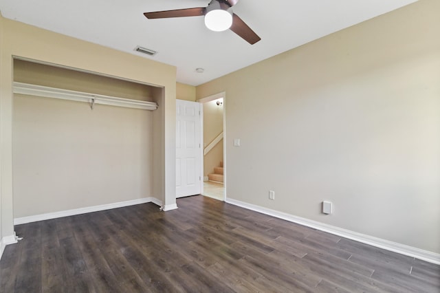 unfurnished bedroom with ceiling fan, dark wood-type flooring, and a closet