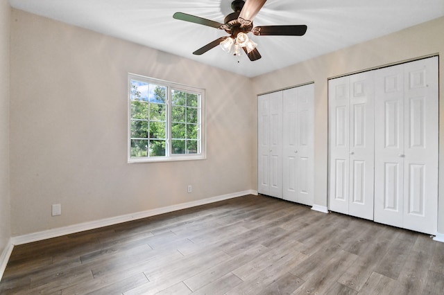 unfurnished bedroom featuring ceiling fan, two closets, and light hardwood / wood-style flooring