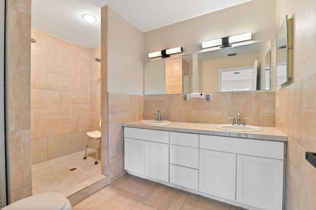 bathroom with tile patterned flooring, tile walls, tiled shower, and vanity