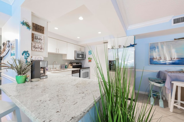 kitchen featuring stainless steel appliances, tasteful backsplash, crown molding, light stone countertops, and white cabinets