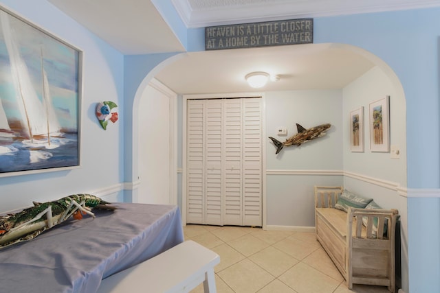 bedroom with crown molding, a closet, and light tile flooring