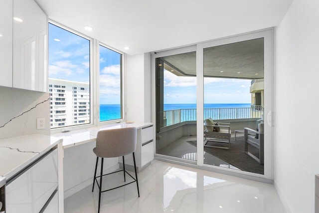 interior space featuring a healthy amount of sunlight, a water view, and light tile floors