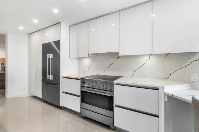 kitchen with light tile flooring, stainless steel appliances, tasteful backsplash, white cabinetry, and light stone countertops