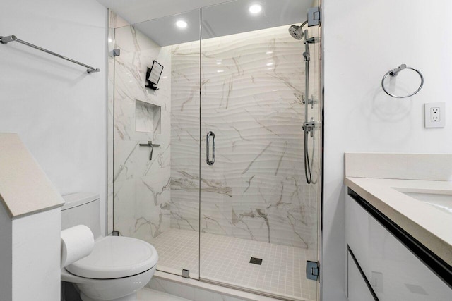 bathroom with a shower with shower door, vanity, and toilet