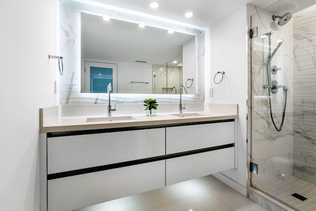 bathroom with a shower with shower door, oversized vanity, dual sinks, and tile floors