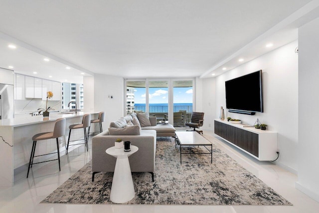 living room featuring a water view, expansive windows, sink, and light tile flooring