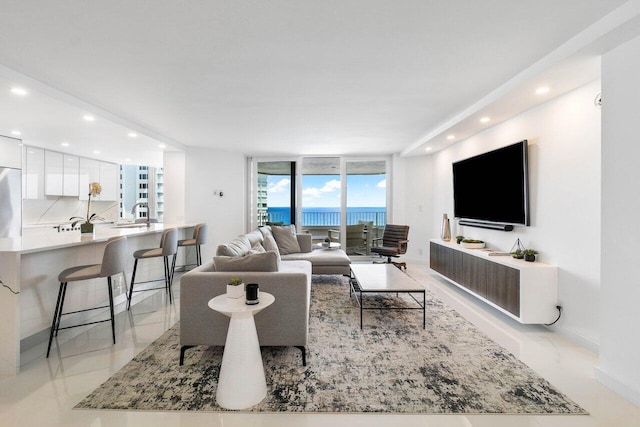 living room featuring a water view, light tile flooring, and a wall of windows