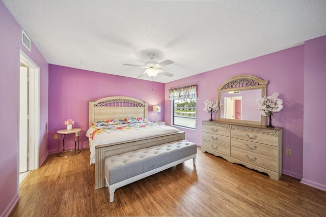 bedroom with hardwood / wood-style floors, a textured ceiling, and ceiling fan