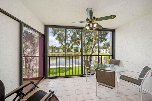 sunroom / solarium featuring ceiling fan and a water view