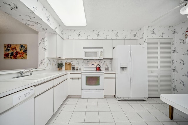 kitchen featuring light tile patterned flooring, white appliances, white cabinetry, and sink