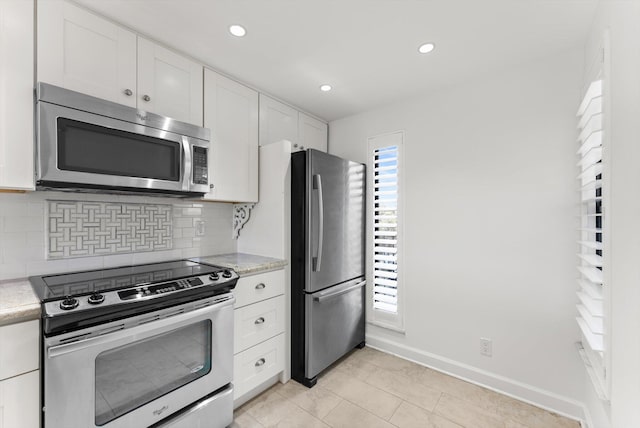 kitchen with appliances with stainless steel finishes, white cabinetry, tasteful backsplash, and light tile floors