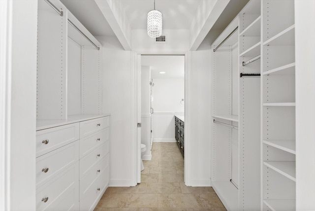 spacious closet with an inviting chandelier and light tile floors