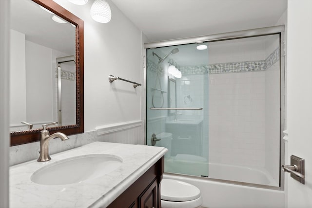 full bathroom with combined bath / shower with glass door, vanity, and toilet