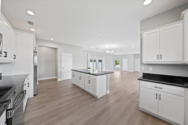 kitchen featuring light hardwood / wood-style floors, white cabinetry, a chandelier, and appliances with stainless steel finishes