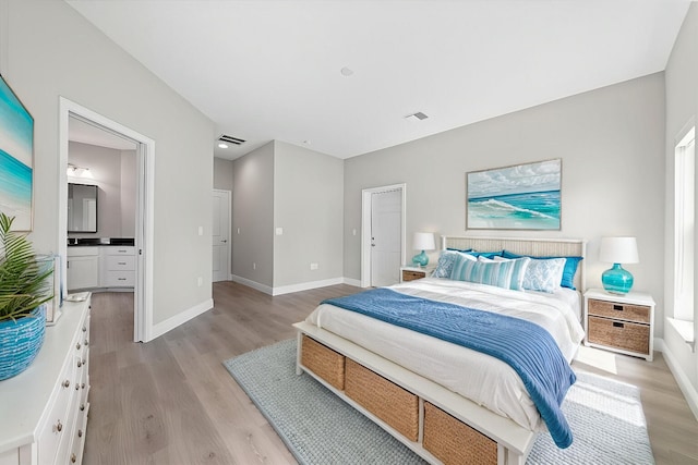 bedroom with ensuite bathroom and light wood-type flooring