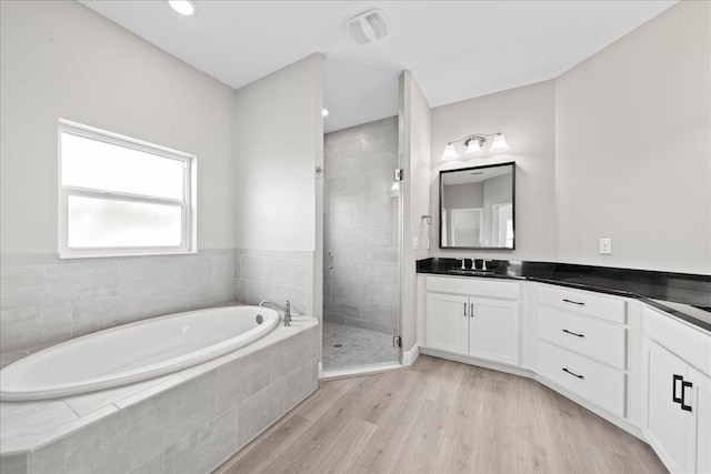 bathroom with wood-type flooring, vanity, and independent shower and bath