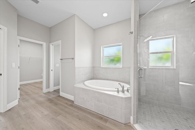 bathroom with a wealth of natural light, hardwood / wood-style floors, and shower with separate bathtub