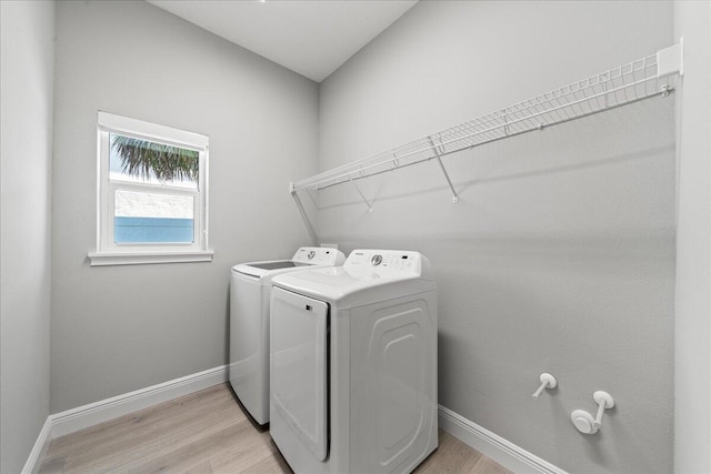 clothes washing area with separate washer and dryer and light hardwood / wood-style flooring