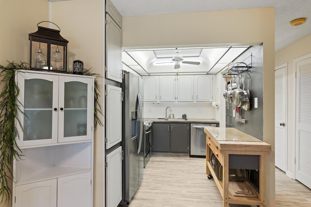 kitchen featuring appliances with stainless steel finishes, tasteful backsplash, light hardwood / wood-style floors, sink, and gray cabinetry