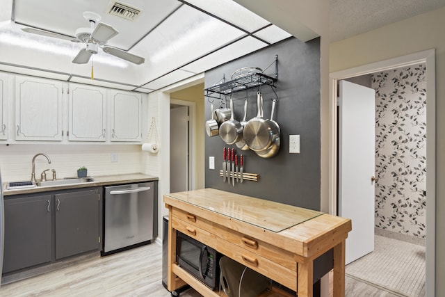 kitchen featuring ceiling fan, backsplash, stainless steel dishwasher, sink, and white cabinets