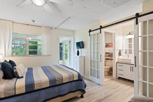 bedroom with ceiling fan, sink, a textured ceiling, and ensuite bathroom