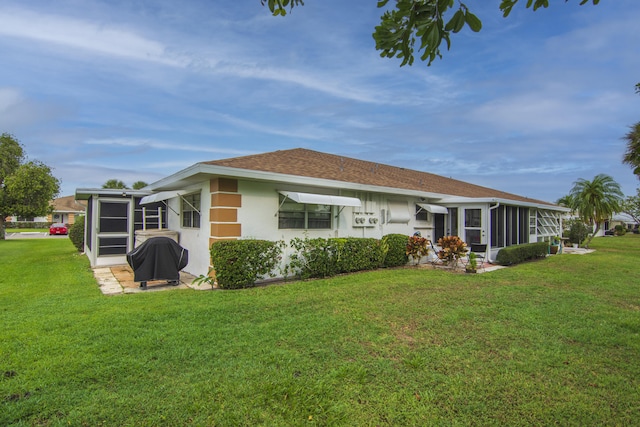 back of property featuring a sunroom and a lawn