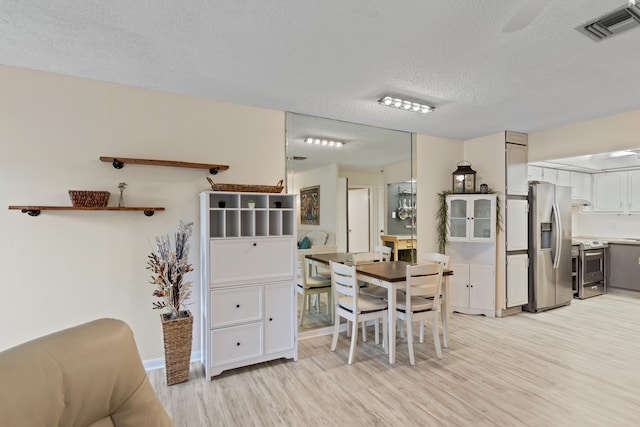 dining area featuring light hardwood / wood-style floors and a textured ceiling