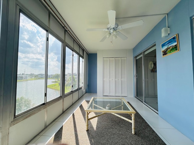 sunroom with ceiling fan and a water view