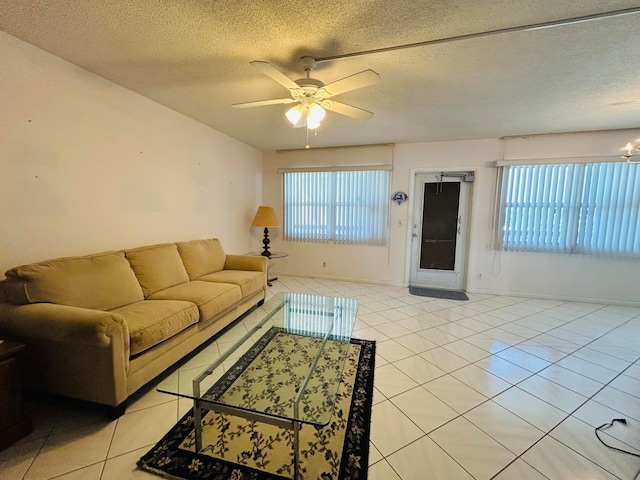 living room with a textured ceiling, ceiling fan, and light tile floors