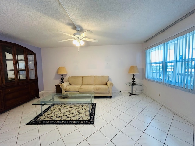 living room featuring a textured ceiling, ceiling fan, and light tile flooring