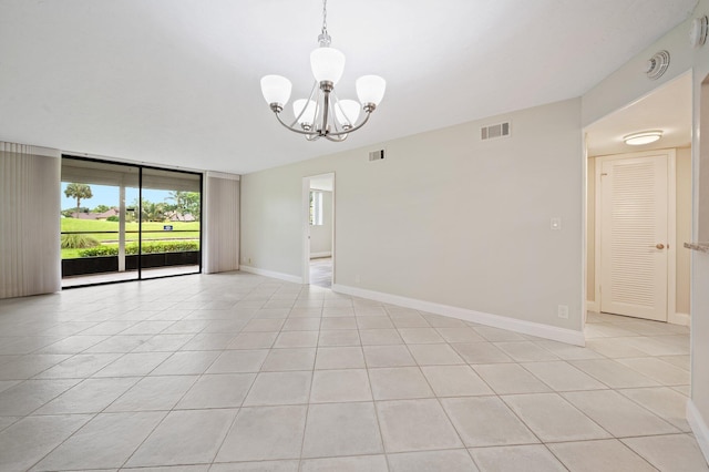 tiled spare room with floor to ceiling windows and a notable chandelier