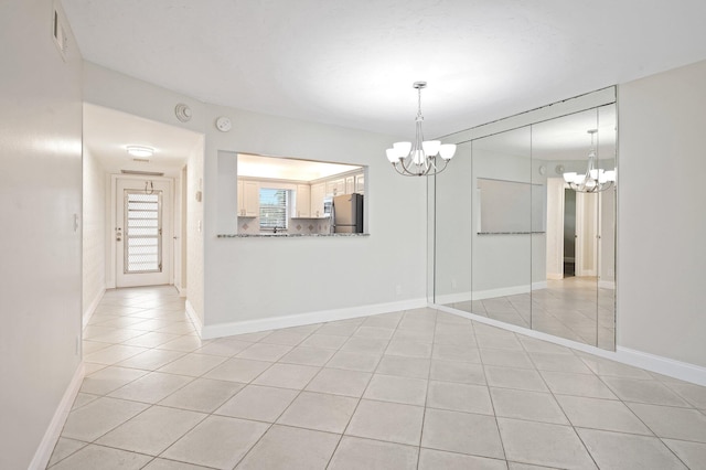 unfurnished dining area with an inviting chandelier and light tile patterned floors