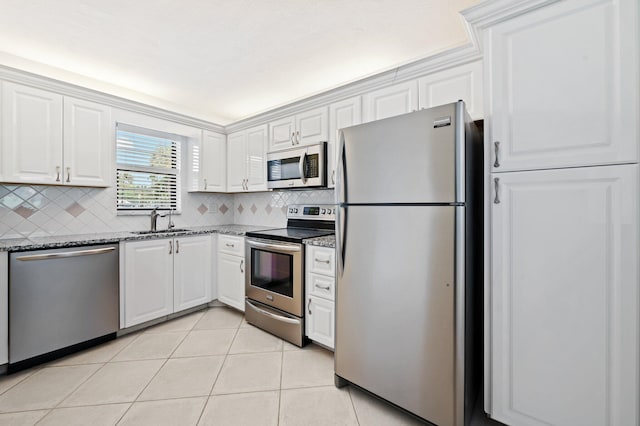 kitchen featuring sink, white cabinetry, dark stone countertops, appliances with stainless steel finishes, and decorative backsplash