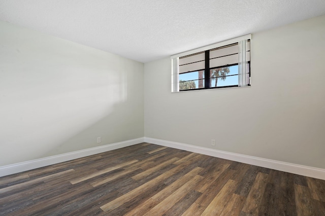 spare room with a textured ceiling and dark wood-type flooring