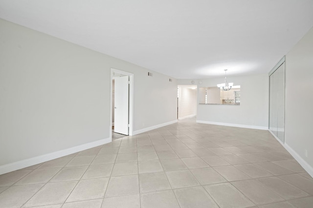 empty room with light tile patterned flooring and a chandelier