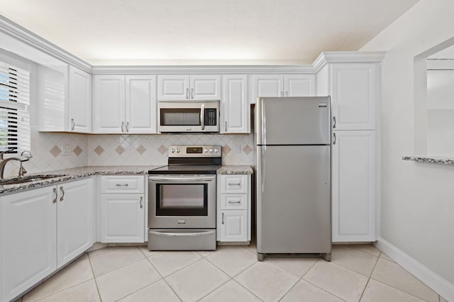 kitchen with sink, light stone countertops, light tile patterned floors, white cabinetry, and stainless steel appliances