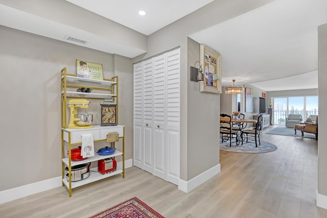 hallway with an inviting chandelier and light hardwood / wood-style flooring