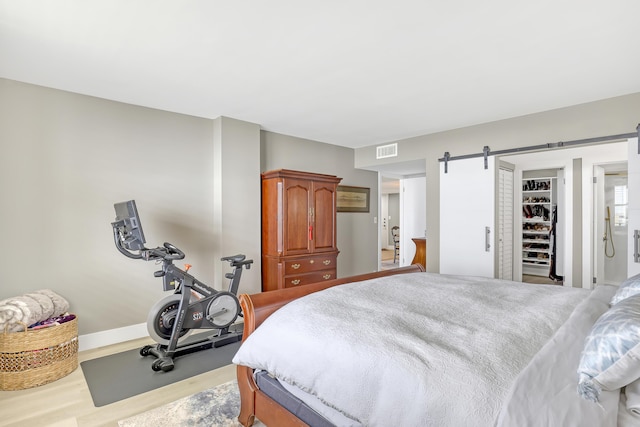 bedroom with a barn door and light hardwood / wood-style floors