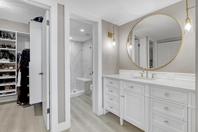 bathroom with hardwood / wood-style floors, vanity, toilet, and walk in shower