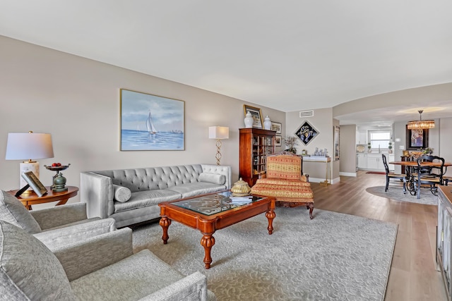 living room with light hardwood / wood-style floors and a notable chandelier