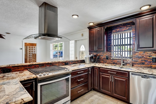 kitchen with light stone countertops, sink, stainless steel appliances, wall chimney range hood, and light tile patterned floors