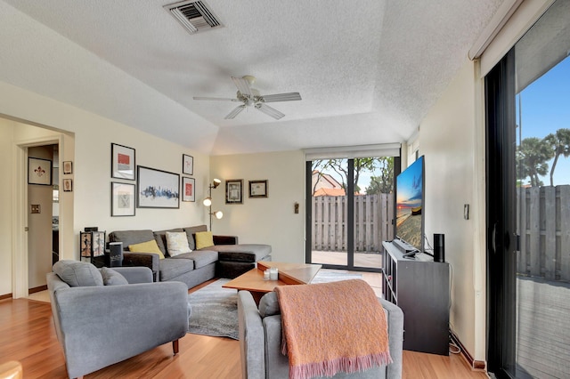 living room featuring ceiling fan, light hardwood / wood-style floors, a textured ceiling, and vaulted ceiling