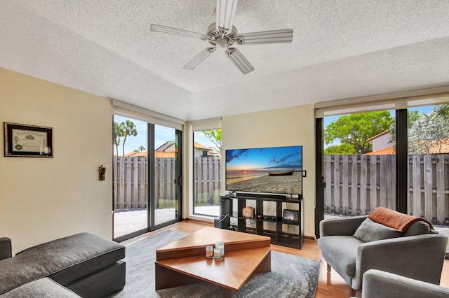 living room with ceiling fan, light hardwood / wood-style floors, and a textured ceiling