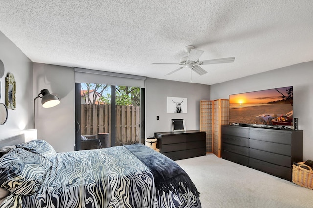 carpeted bedroom featuring access to outside, ceiling fan, and a textured ceiling