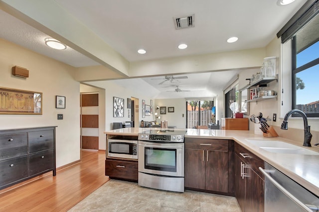 kitchen featuring a healthy amount of sunlight, dark brown cabinets, stainless steel appliances, and sink