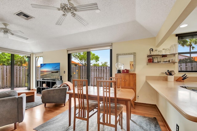 dining room featuring a textured ceiling, ceiling fan, light hardwood / wood-style floors, and lofted ceiling