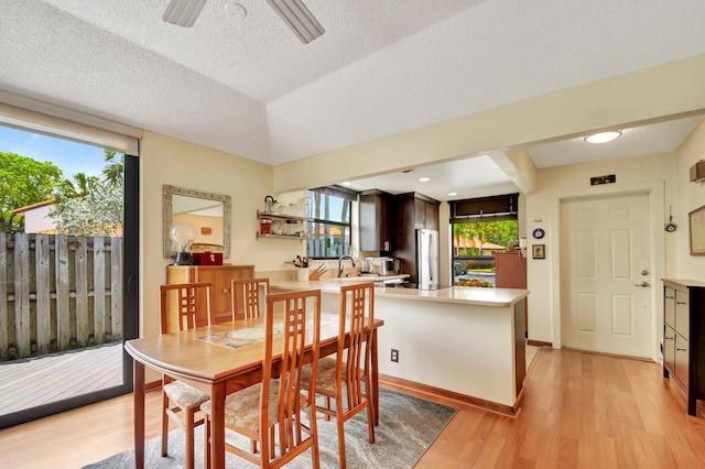 dining area with ceiling fan, light wood-type flooring, sink, and vaulted ceiling