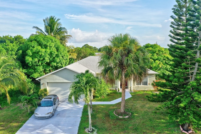 view of property hidden behind natural elements featuring a garage and a front yard