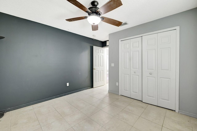 unfurnished bedroom with light tile patterned flooring, ceiling fan, and a closet